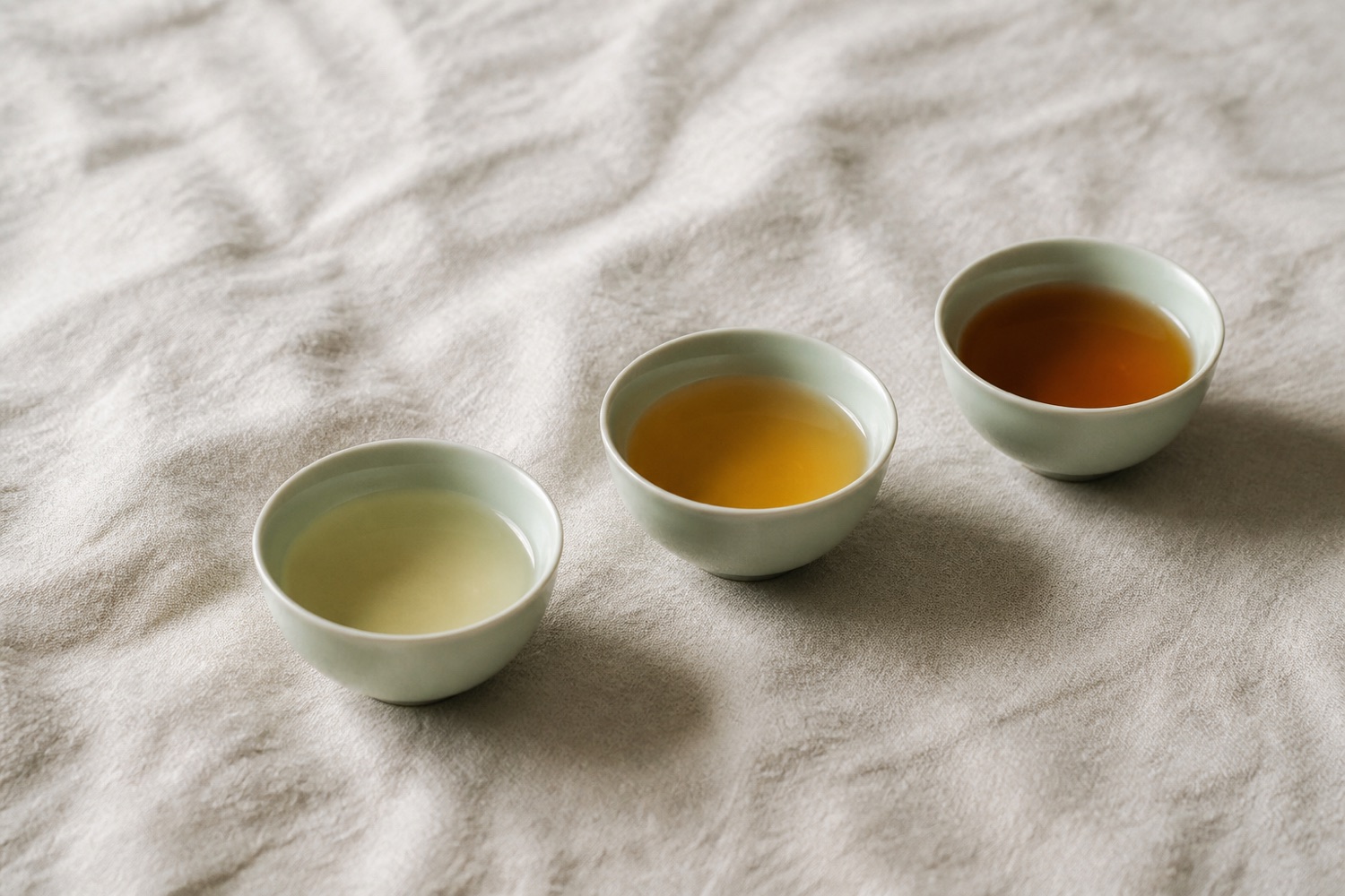 Three celadon cups holding tea liquor in three different shades