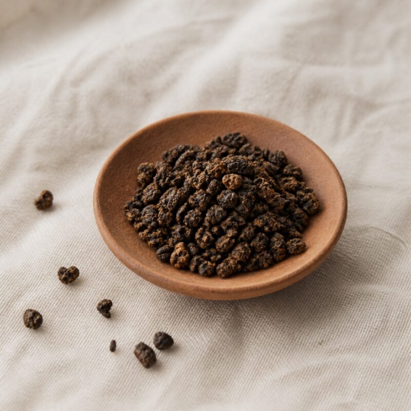 Dark amber roasted oolong pellets in an unglazed clay dish