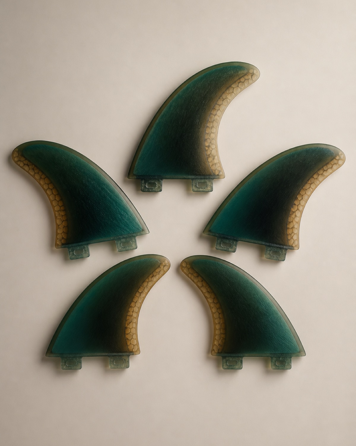 Five fibreglass surfboard fins fanned out on a sand backdrop