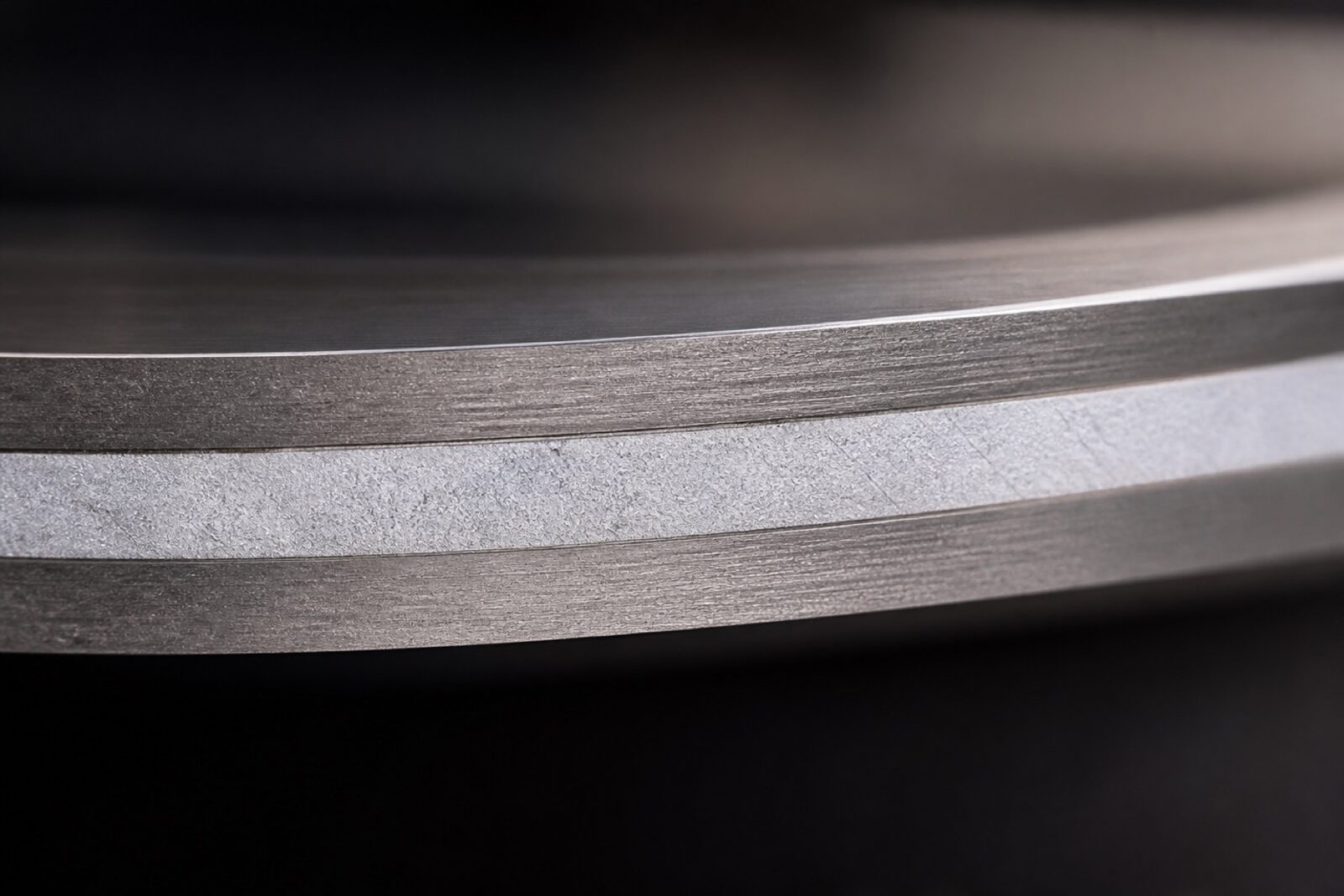 Macro of a tri-ply pan base showing the aluminium core between steel layers