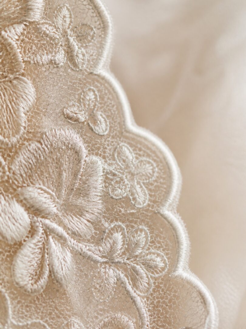 Extreme close up of ivory scalloped french lace with floral embroidery