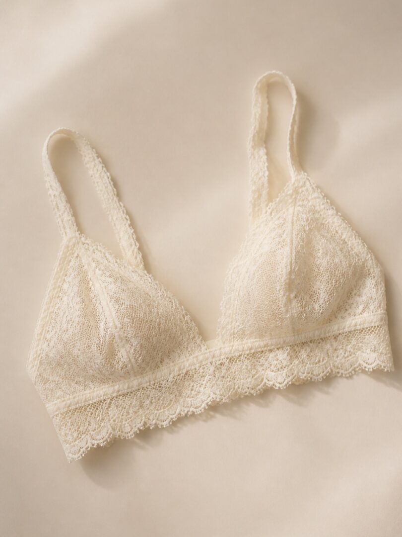An ivory french-lace bralette arranged flat on a cream backdrop