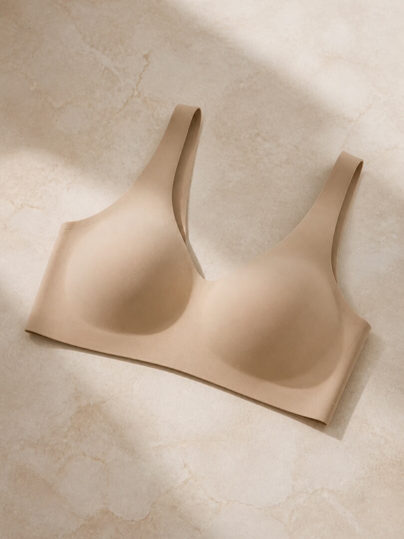 A seamless wireless bra in warm sand photographed flat on pale stone